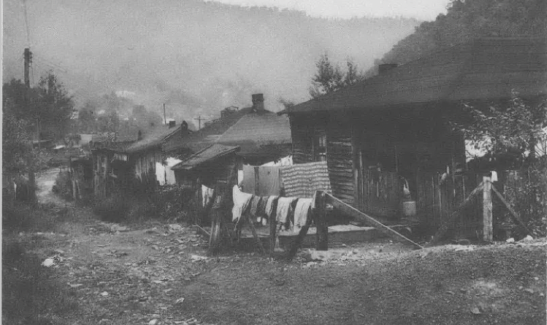 Black and white photo of clothes hanging on drying line outside house