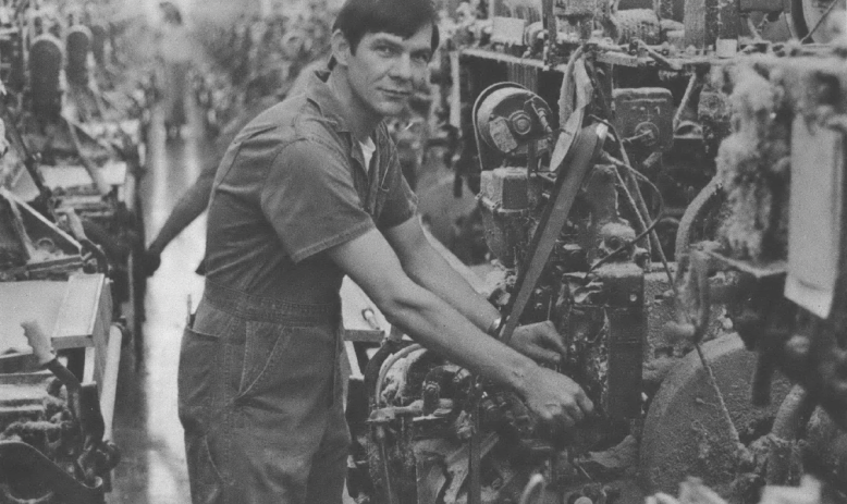 Black and white photo of man standing at machine