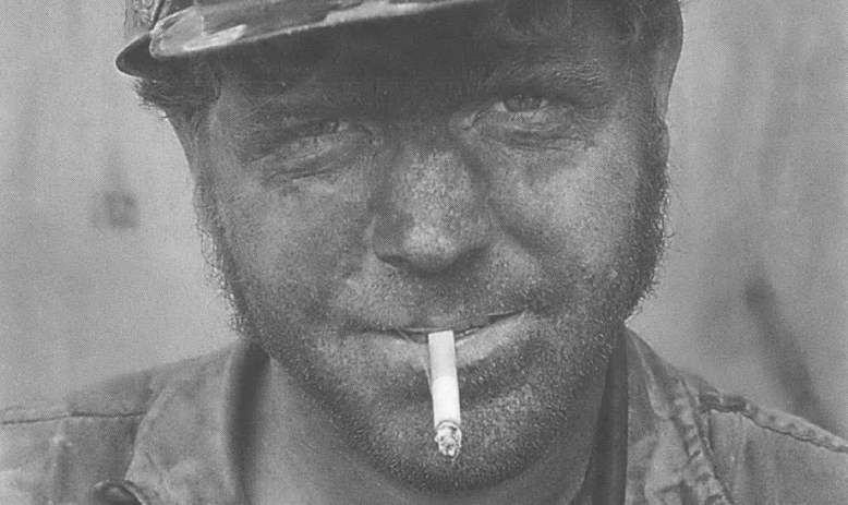Coal miner in hard hat smoking cigarette