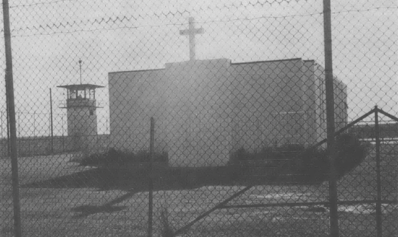 A white church behind a prison fence, next to a guard tower