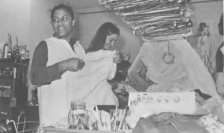 Black and white photo of women standing and working in an office