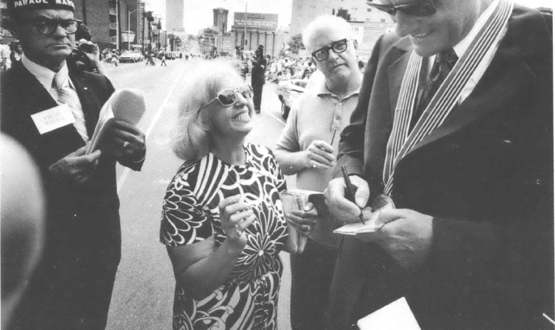 Black and white photo of middle-aged Billy Graham surrounded by admirers 