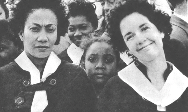 Three Black women and a Black girl, of varying skin tones, wearing uniforms and looking at the camera