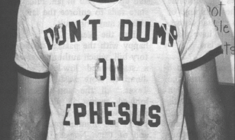 Black and white photo of young white man in baseball cap and shirt reading "Don't Dump on Ephesus"