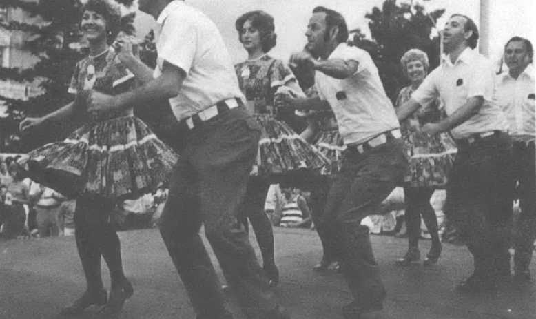 Black and white photo of men and women dancing on a street outside