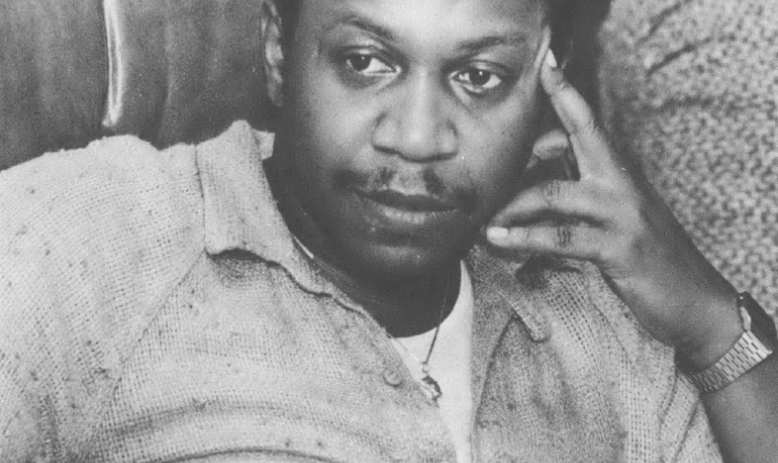 Photo portrait of seated Black man with hand to head, looking away from the camera