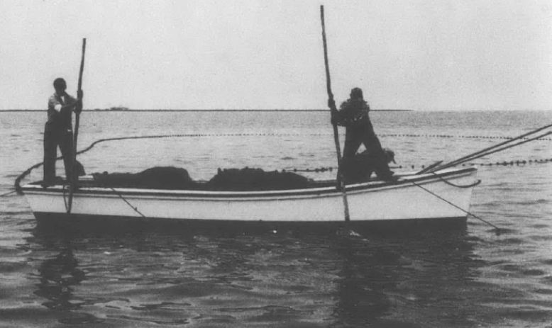 Black and white photo of two men on canoe-shaped boat