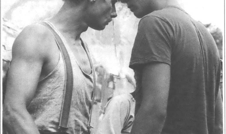 Black and white photo of two men head to head with each other on stage looking into each others' eyes