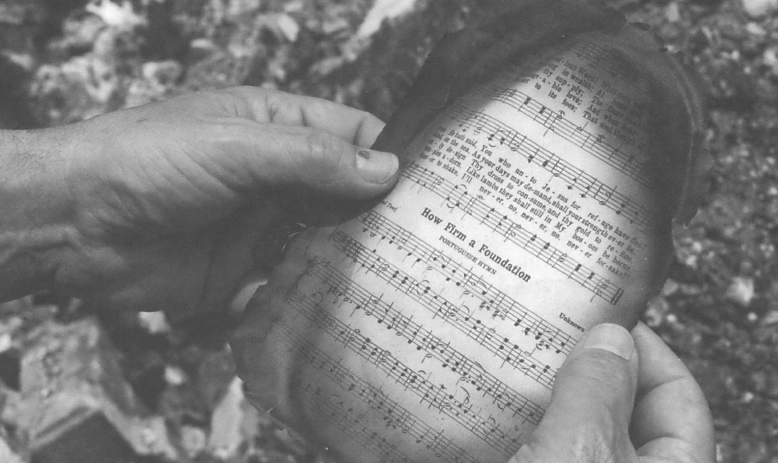 Hands holding a scorched hymnbook page