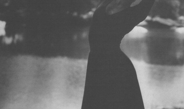 Black and white photo of woman posing as if dancing in front of water