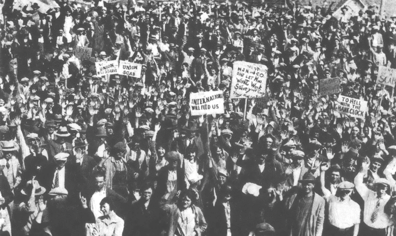 Black and white photo of crowd of people, some of them holding signs