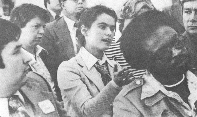 Black and white photo of people listening to speaker