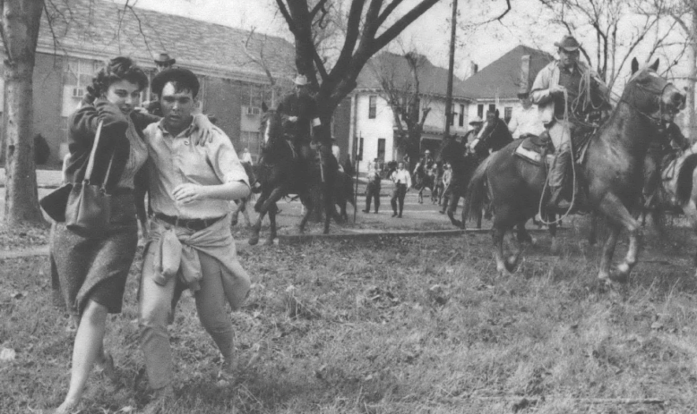 Black and white photo of people running from cops on horseback in a neighborhood