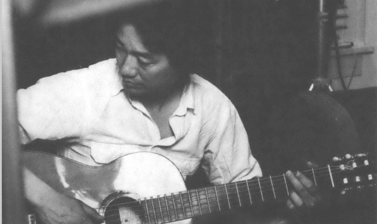 Black and white photo of Eugene Jo holding a guitar