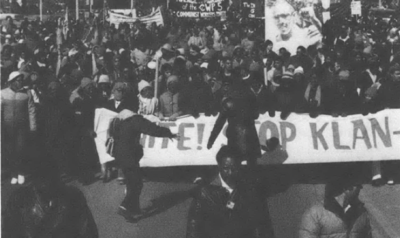 Black and white photo of demonstrators holding anti-Klan sign