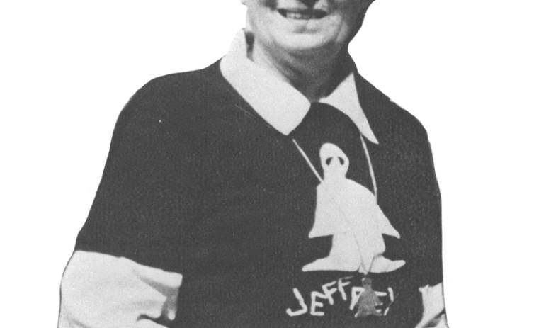 Black and white photo of older woman wearing glasses and t-shirt layered over collared shirt 