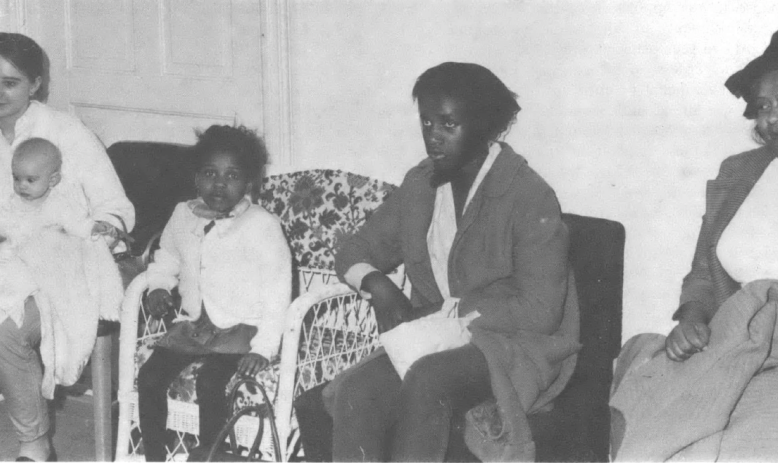 Black and white photo of five people—two Black adults, a Black child, a baby, and a white woman—seated in a row.