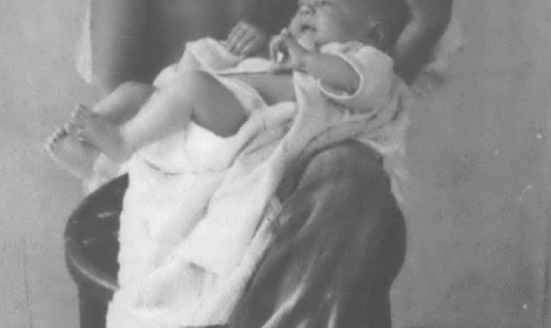 Black and white photo of child holding a baby