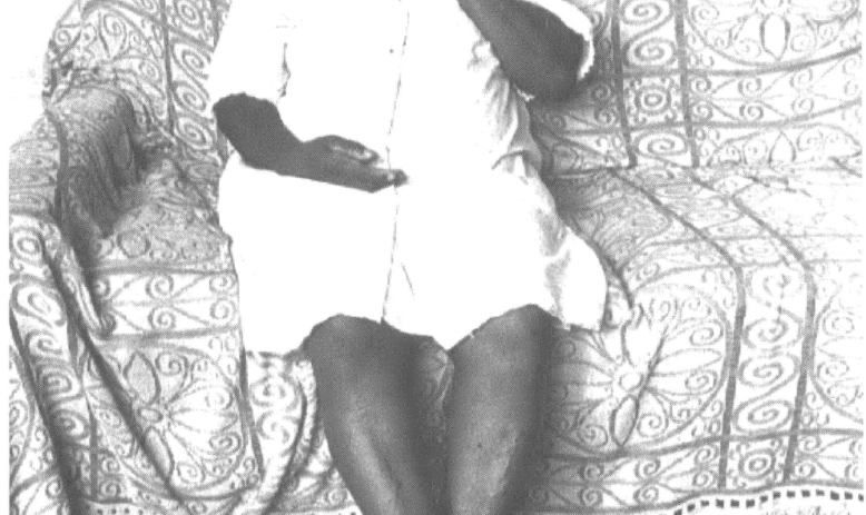 Black woman in dress sitting on a sofa in the home