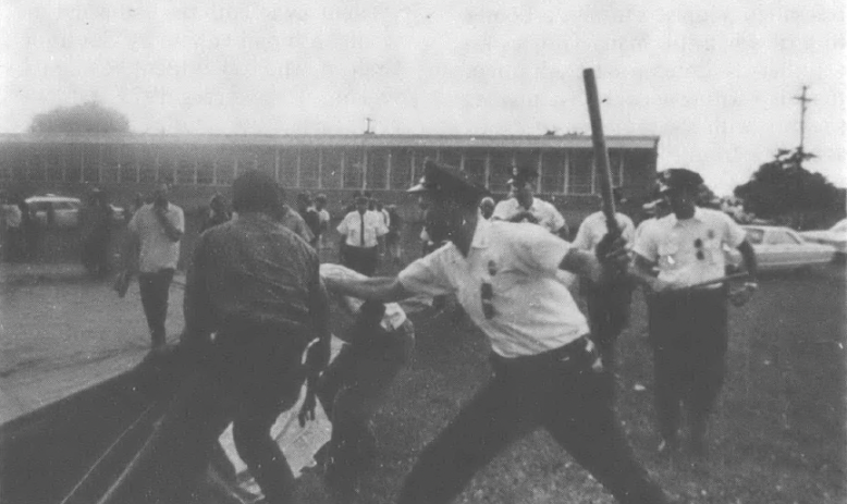 Black and white photo of police beating demonstrators