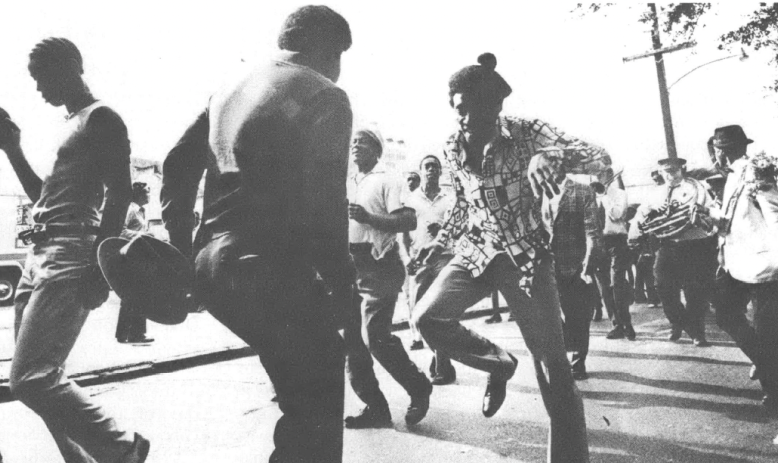 Black and white photo of people, mostly Black, dancing in the street