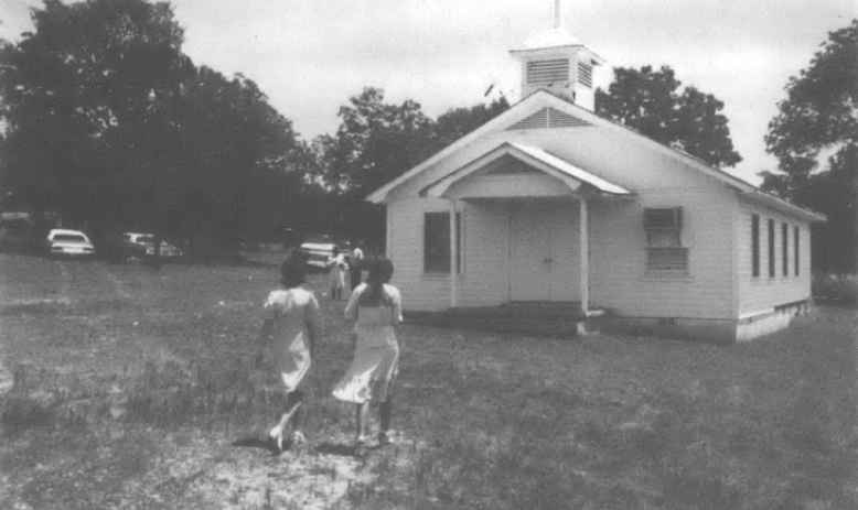Photo of two women walking into a small churchhouse
