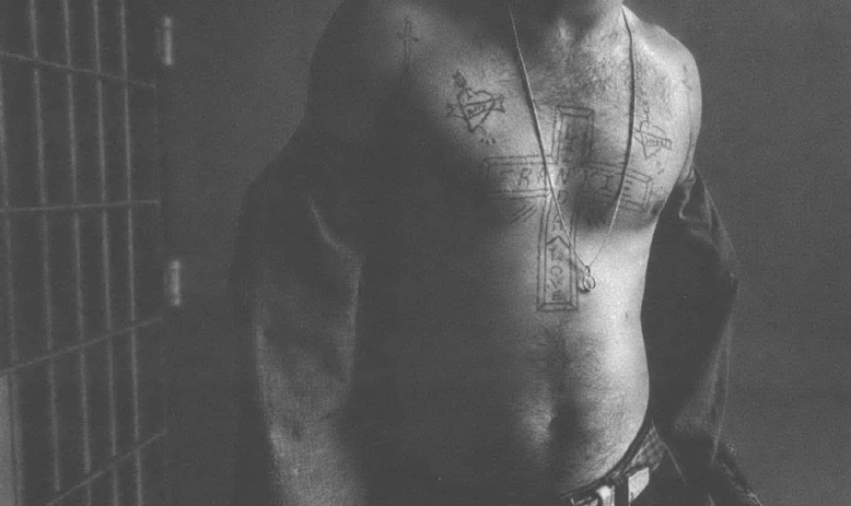 Black and white photo of shirtless man's torso, with tattoos