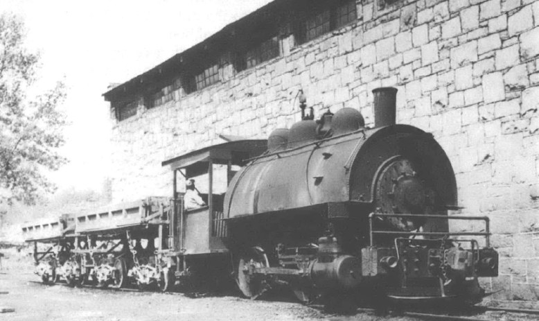 Black and white photo of train engine car in front of brick building