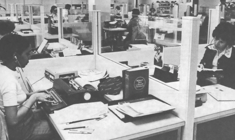 Black and white photo of women working at desks in open office space
