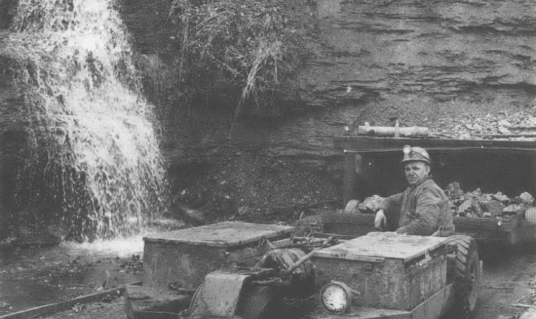 Photo of man on machinery rolling away from mountain or mine