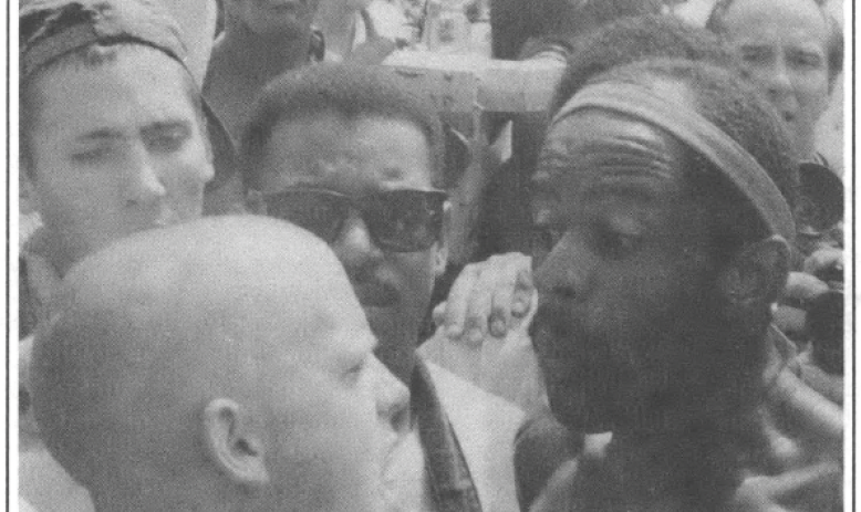 in a crowd of people a bald white man and a african american man apparently confronting each other