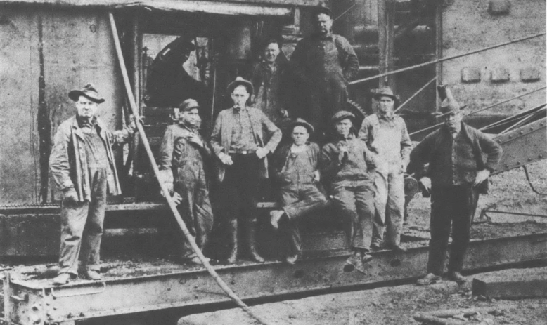 Nine men pose for a photo in a construction site standing on steel structures
