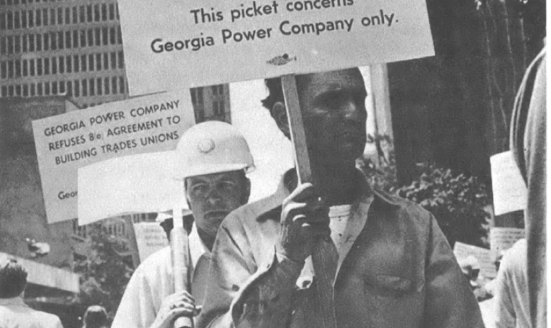 Black and white photo of two people holding signs picketing the Georgia Power Company