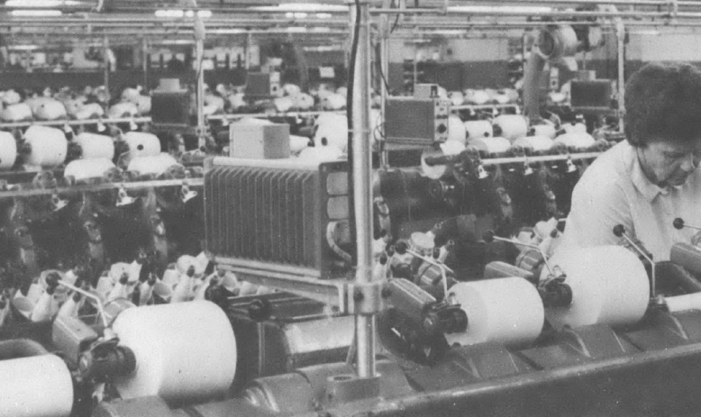 Black and white photo of older white woman with short hair working at a loom