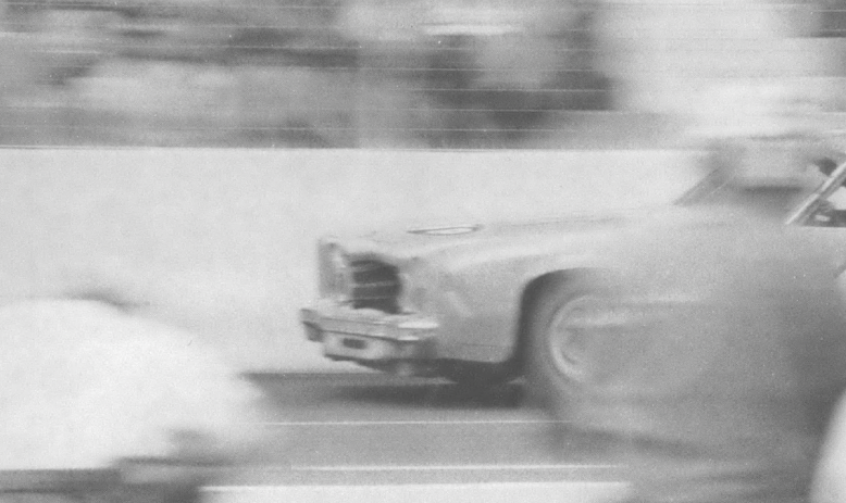 Black and white photo of racing car in motion on track