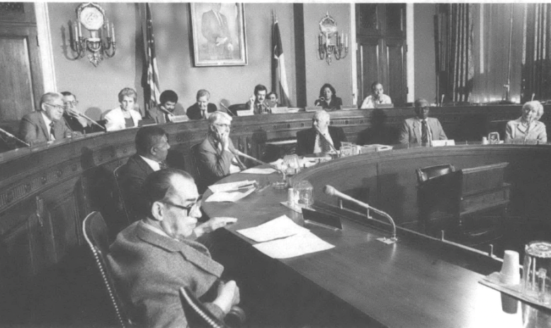 People in a legislative chamber or conference room of some kind