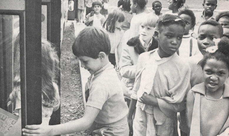 Black and white photo of students boarding a bus