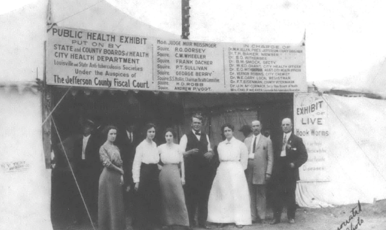 Black and white photo of people in nineteenth century dress standing in front of a church