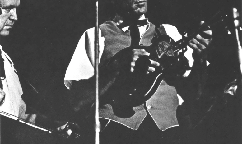 Black and white photo of white man playing mandolin and wearing a cowboy hat