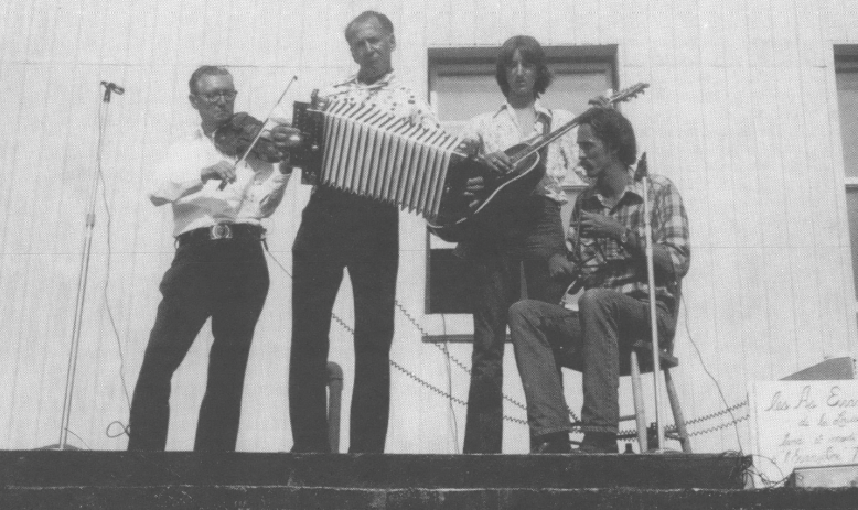 Photo of band with guitar, accordion, fiddle playing on stage