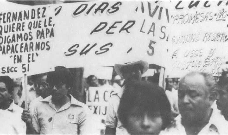 Black and white photo of people with signs, many in Spanish
