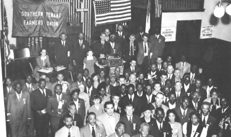 Black and white photo of a gathering of people standing inside a church