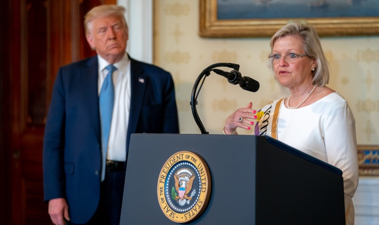 Cleta Mitchell talking at White House podium with President Trump standing behind her