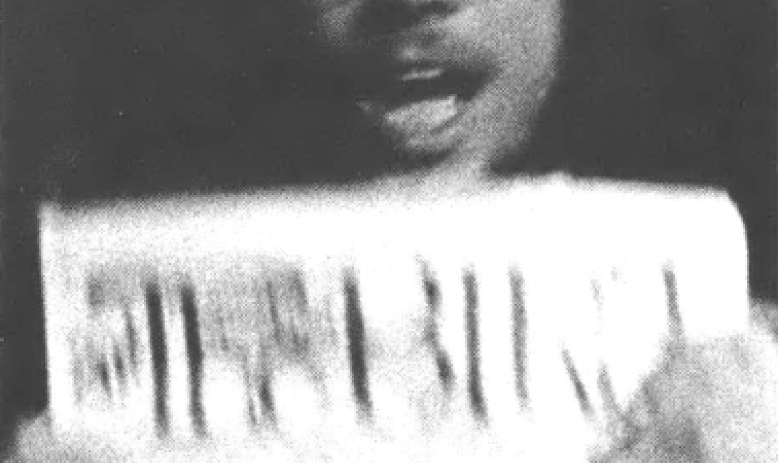 Black and white photo of a man in eyeglasses holding up a newspaper