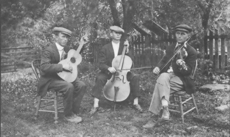 Black and white photo of all-white string band in nineteenth century or early twentieth dress, seated outside in a playing circle
