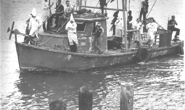 Klan members in Klan robes on a shrimping boat