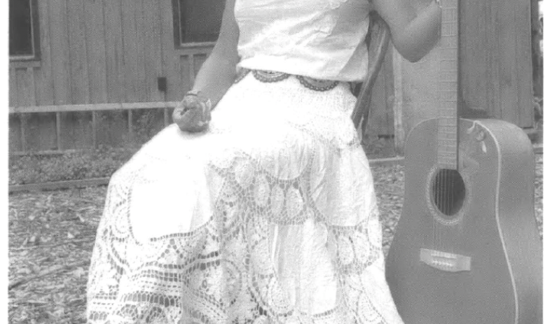 Woman posing with a guitar outside