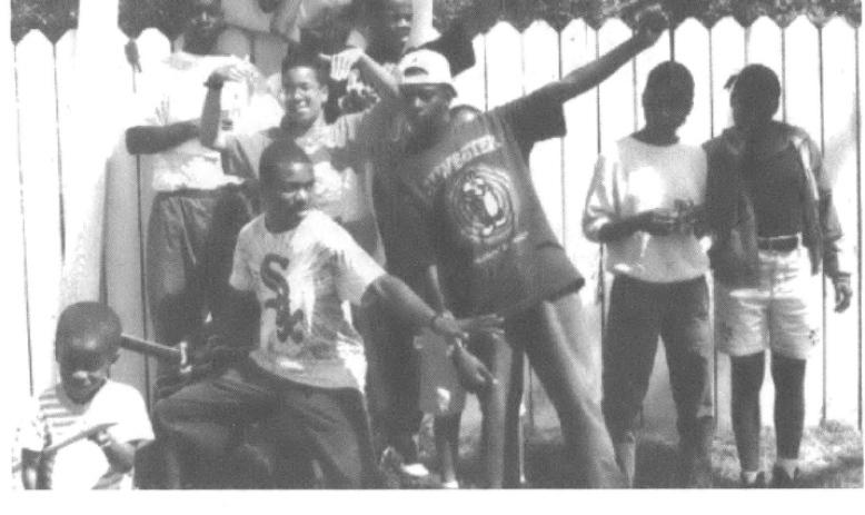 Group of Black kids poses in front of a white picket fence