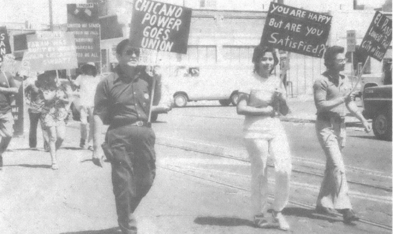 Black and white photo of people marching down street with signs