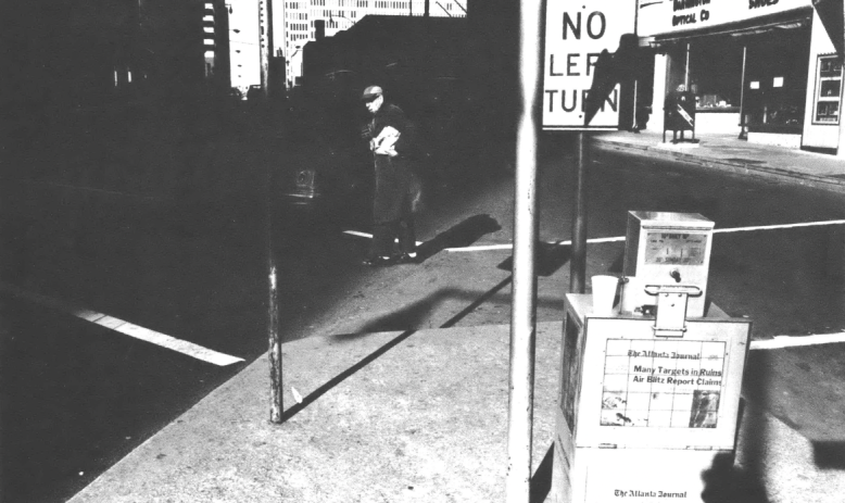 Man walking in city street near newspaper box